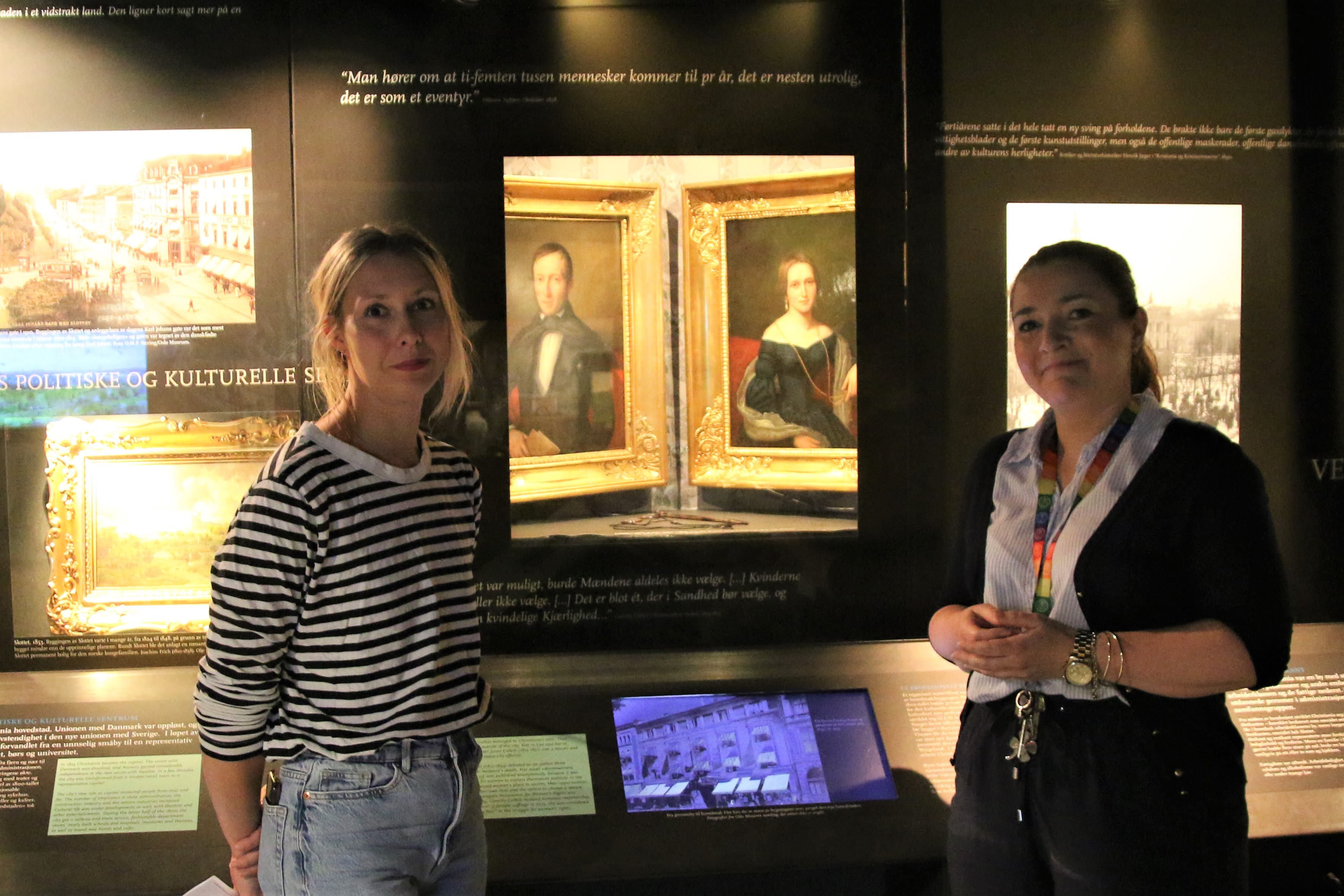 Helene Huljev og Therese Johnsen i foran tablået med bildene av Camilla Collett og ektemannen Jonas Collett i Oslo bymuseum.