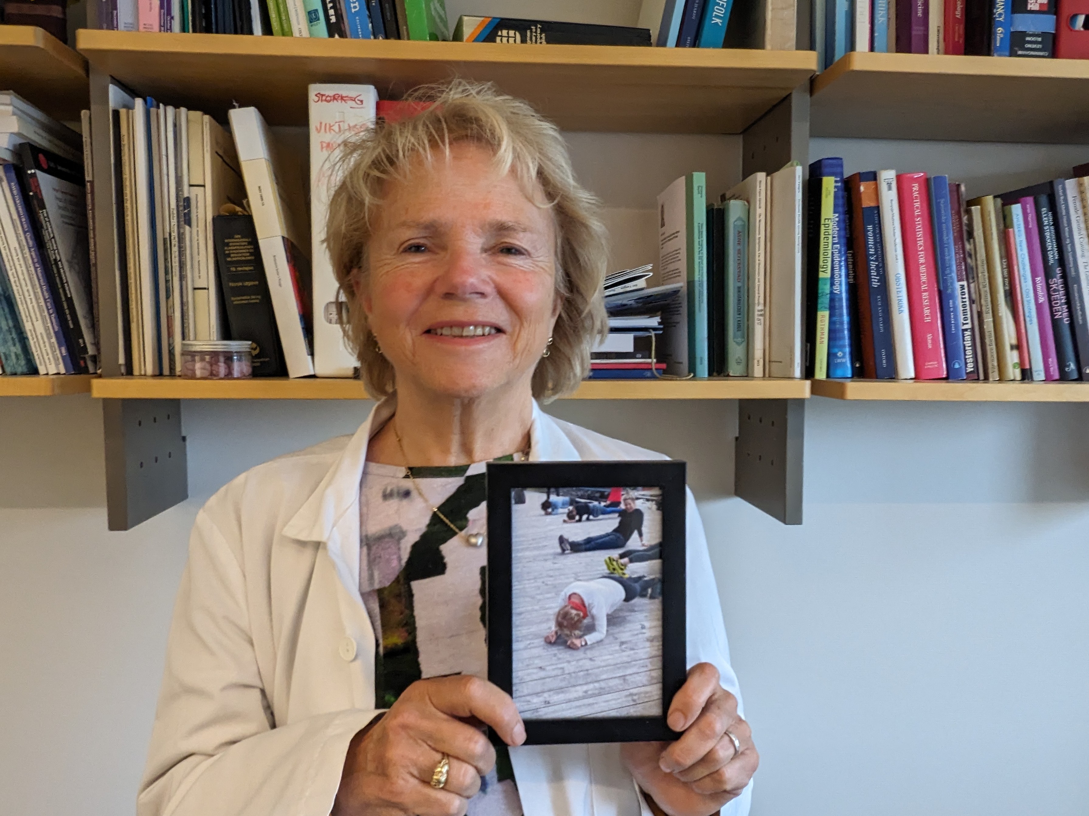 Siri Vangen, professor i kvinnehelse holder opp et fotografi av seg selv som gjør styrketrening